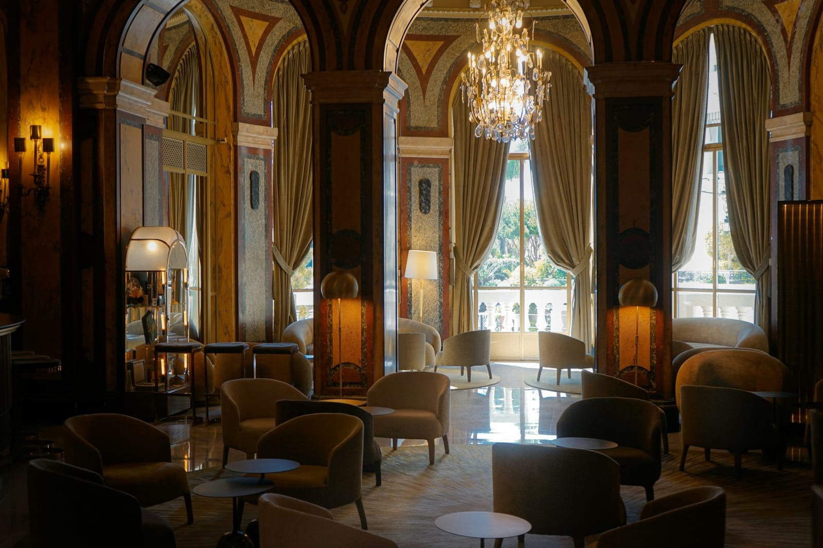 Elegant hotel lounge with chandeliers, tall windows and armchairs
